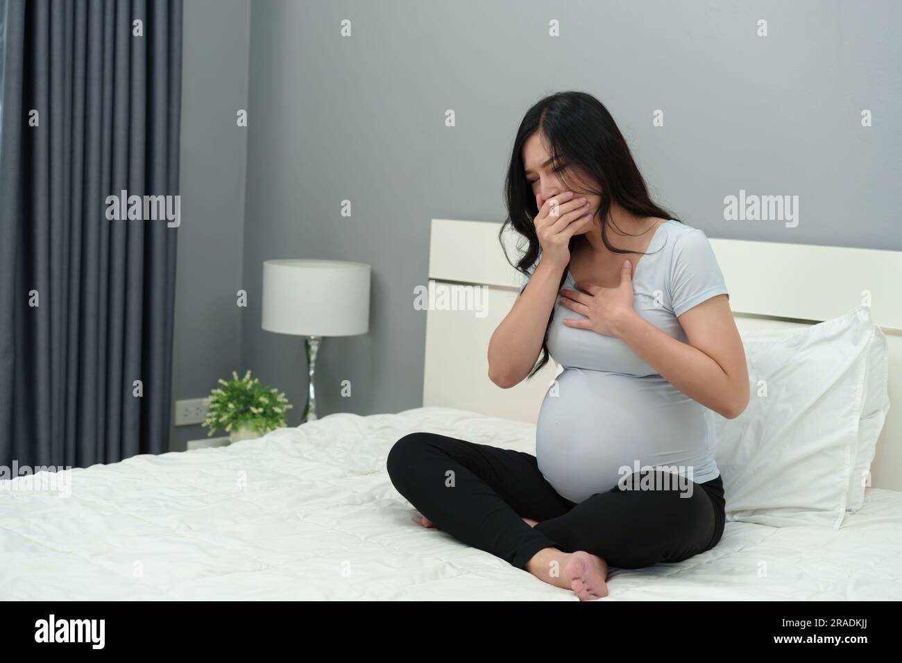 Schwangere Frau fühlt sich schlecht auf einem Bett Stockfoto