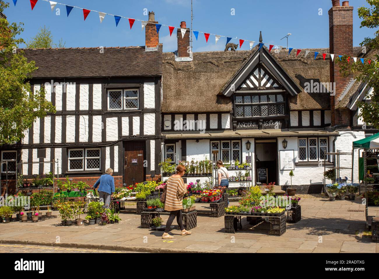 Leute, die an einem Werkstand auf dem Wochenmarkt in der Stadt Cheshire, Sandbach, vor dem Black Bär Coaching Inn aus dem 17. Jahrhundert einkaufen Stockfoto