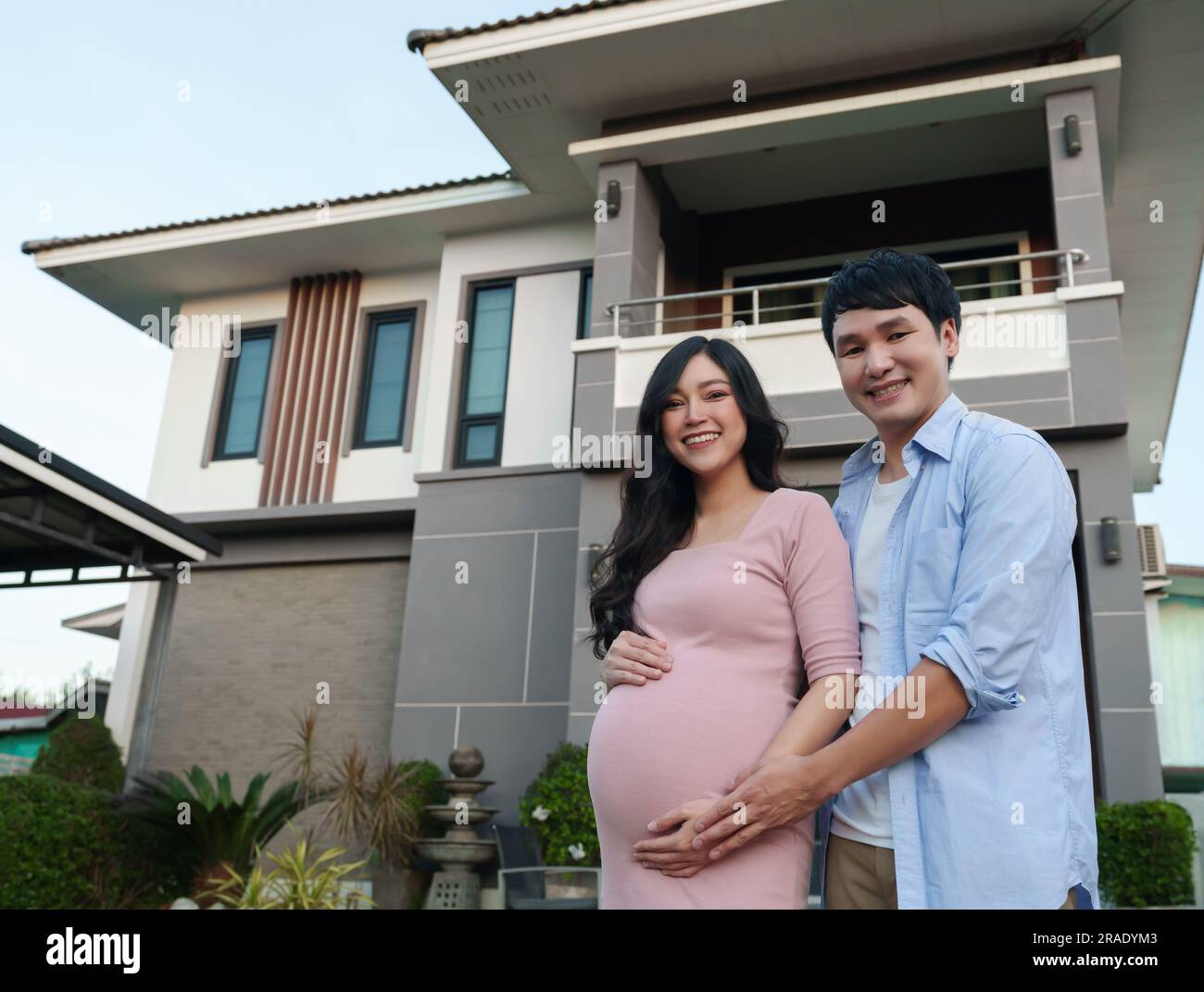 Glückliche Familie steht vor ihrem Haus, Ehemann und schwangere Frau Stockfoto