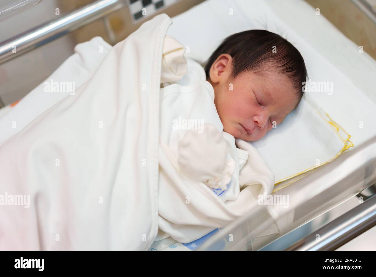 Neugeborene, die im Säuglingskorb im Krankenhaus liegen und schlafen Stockfoto