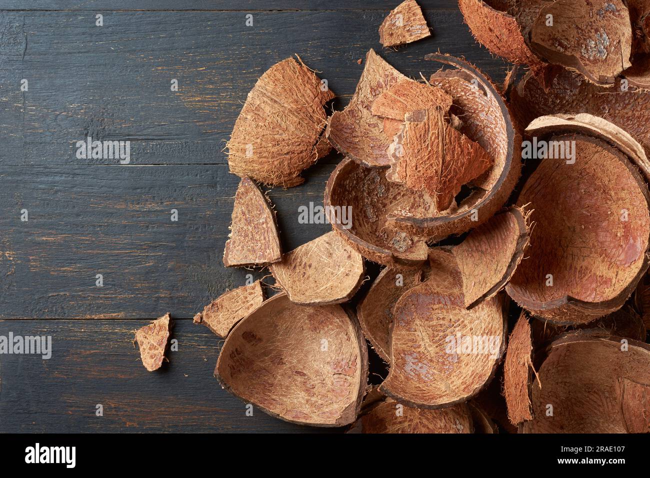 Teile von Kokosnussschalen auf schwarzer Holzoberfläche, kommerziell wichtiges, starkes und haltbares Fasermaterial, als Brennstoff verwendet, Zutat in Stockfoto