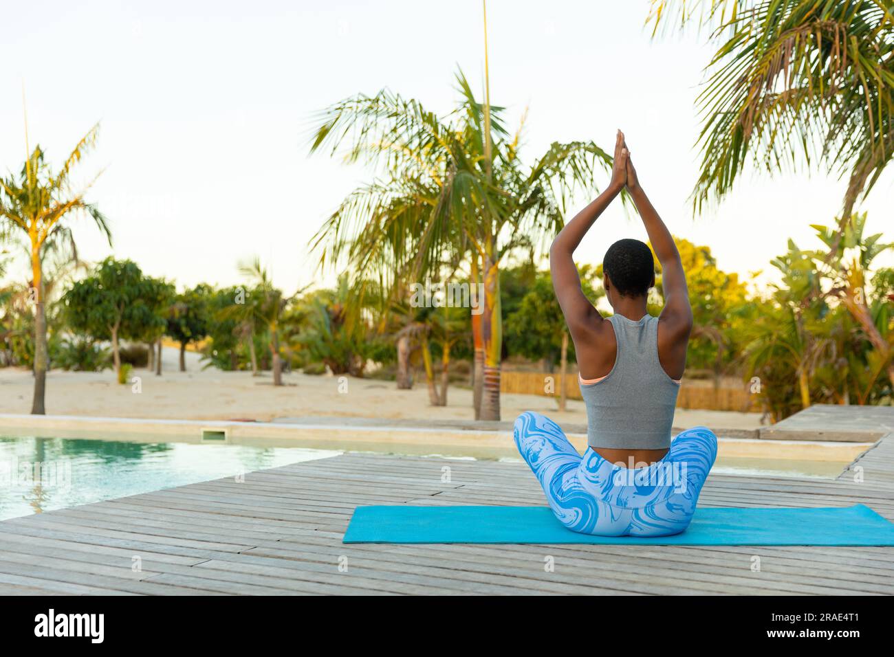 Eine afroamerikanische Frau mit Blick nach hinten, die Yoga-Meditation praktiziert, sitzt auf der Strandterrasse, Kopierbereich Stockfoto