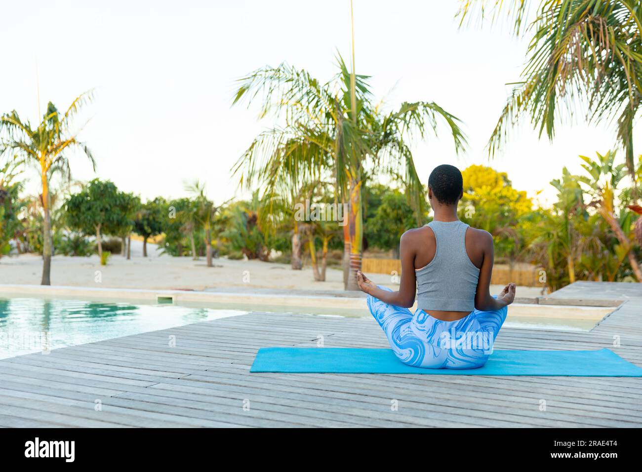 Eine afroamerikanische Frau mit Blick nach hinten, die Yoga-Meditation praktiziert, sitzt auf der Strandterrasse, Kopierbereich Stockfoto