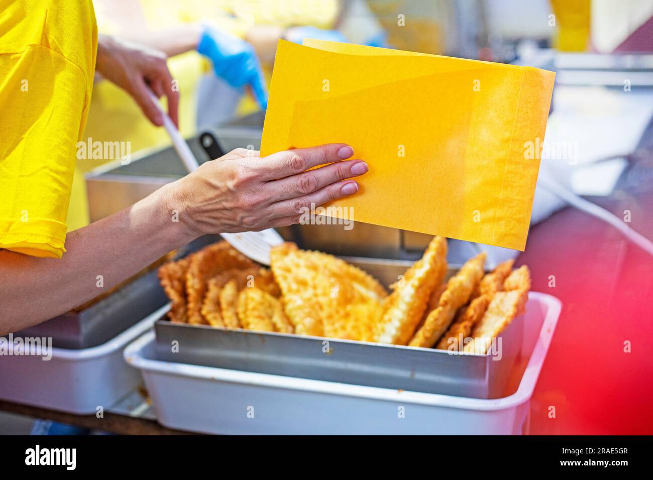 packen Sie einen köstlichen heißen Cheburek in essbares gelbes Papier. Straßenküche, Essen zum Mitnehmen Stockfoto