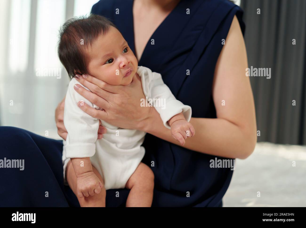 Mutter, die ein Neugeborenes hält und nach der Milchfütterung im Schlafzimmer aufstößt Stockfoto