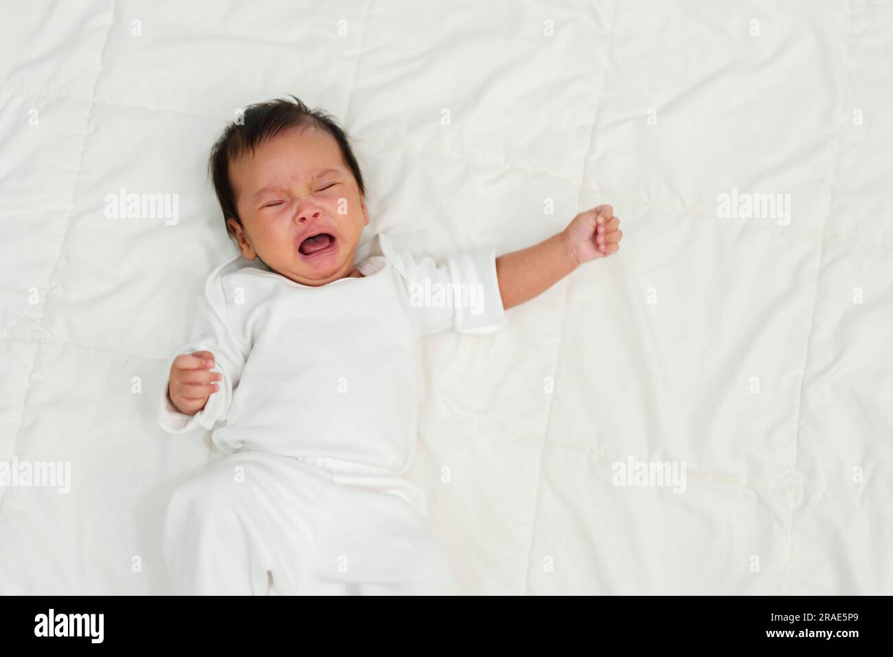 Neugeborenes, das auf einem Bett liegt und weint Stockfoto