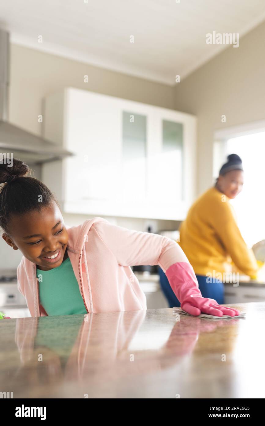 Glückliche afroamerikanische Mutter und Tochter putzten die Arbeitsfläche in der Küche Stockfoto