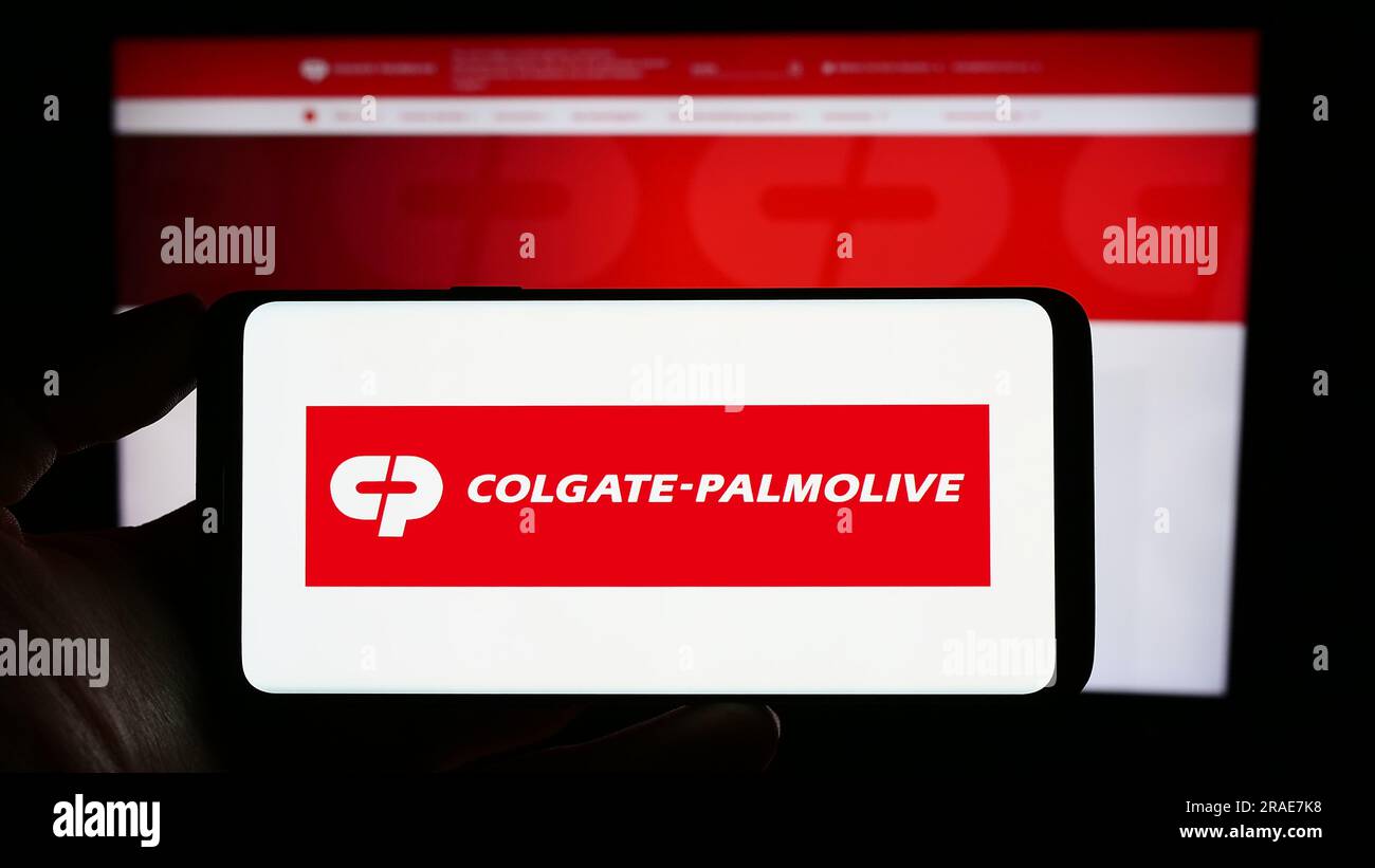 Person, die ein Mobiltelefon mit dem Logo des Konsumgütergeschäfts Colgate-Palmolive Company auf dem Bildschirm vor der Webseite hält. Konzentrieren Sie sich auf das Display des Telefons. Stockfoto