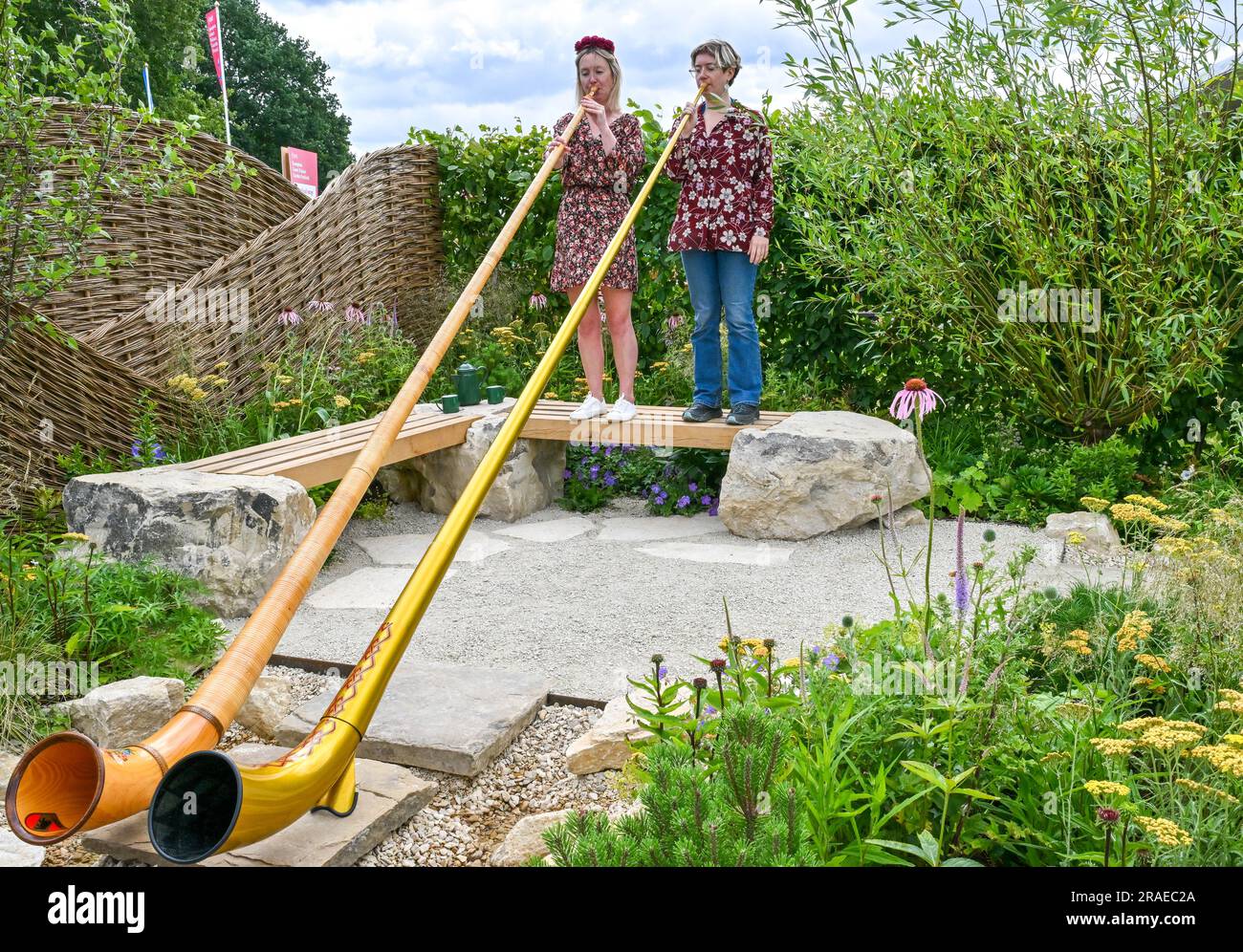 Hampton Court Palace, Surrey, Großbritannien, am 03 2023. Juli. Inghams arbeitet mit Nature Garden zusammen mit zwei Swiss Alphorn-Spielern (L-R) Letty Stott und Robyn Blair beim Hampton Court Palace Garden Festival der RHS am 03 2023. Juli im Hampton Court Palace, Surrey, Großbritannien. Kredit: Francis Knight/Alamy Live News Stockfoto