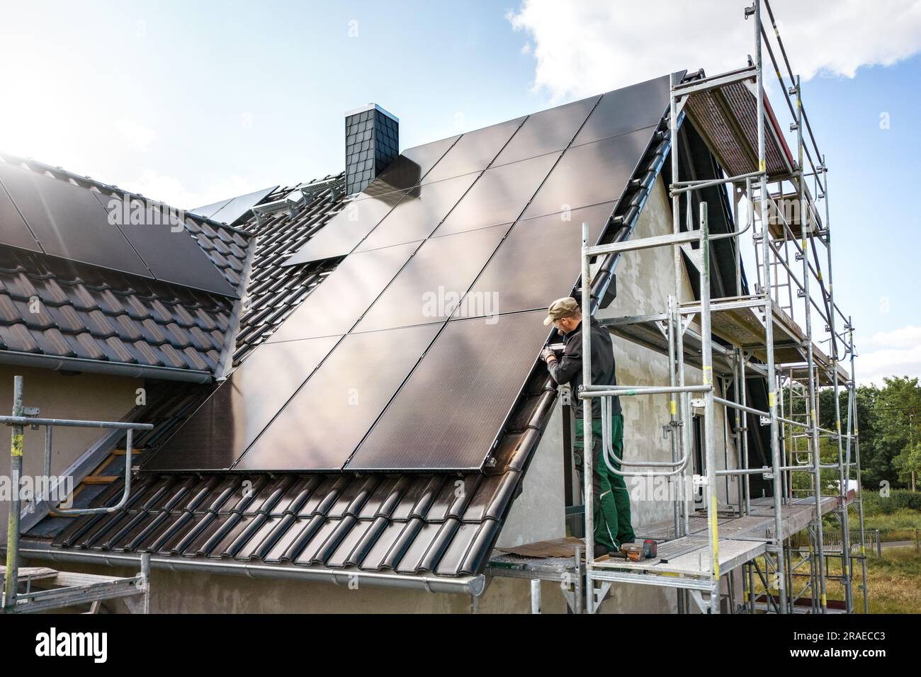 Techniker, der an einem Solarmodul auf einer Baustelle eines Einfamilienhauses arbeitet Stockfoto