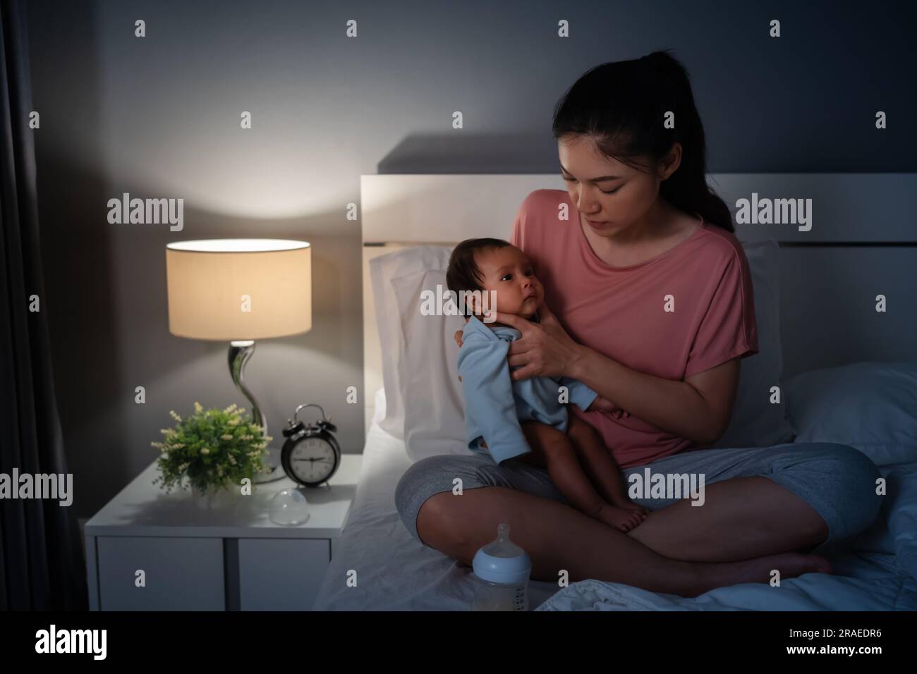 Mutter, die ein Neugeborenes hält und nachts Milch auf einem Bett füttert Stockfoto