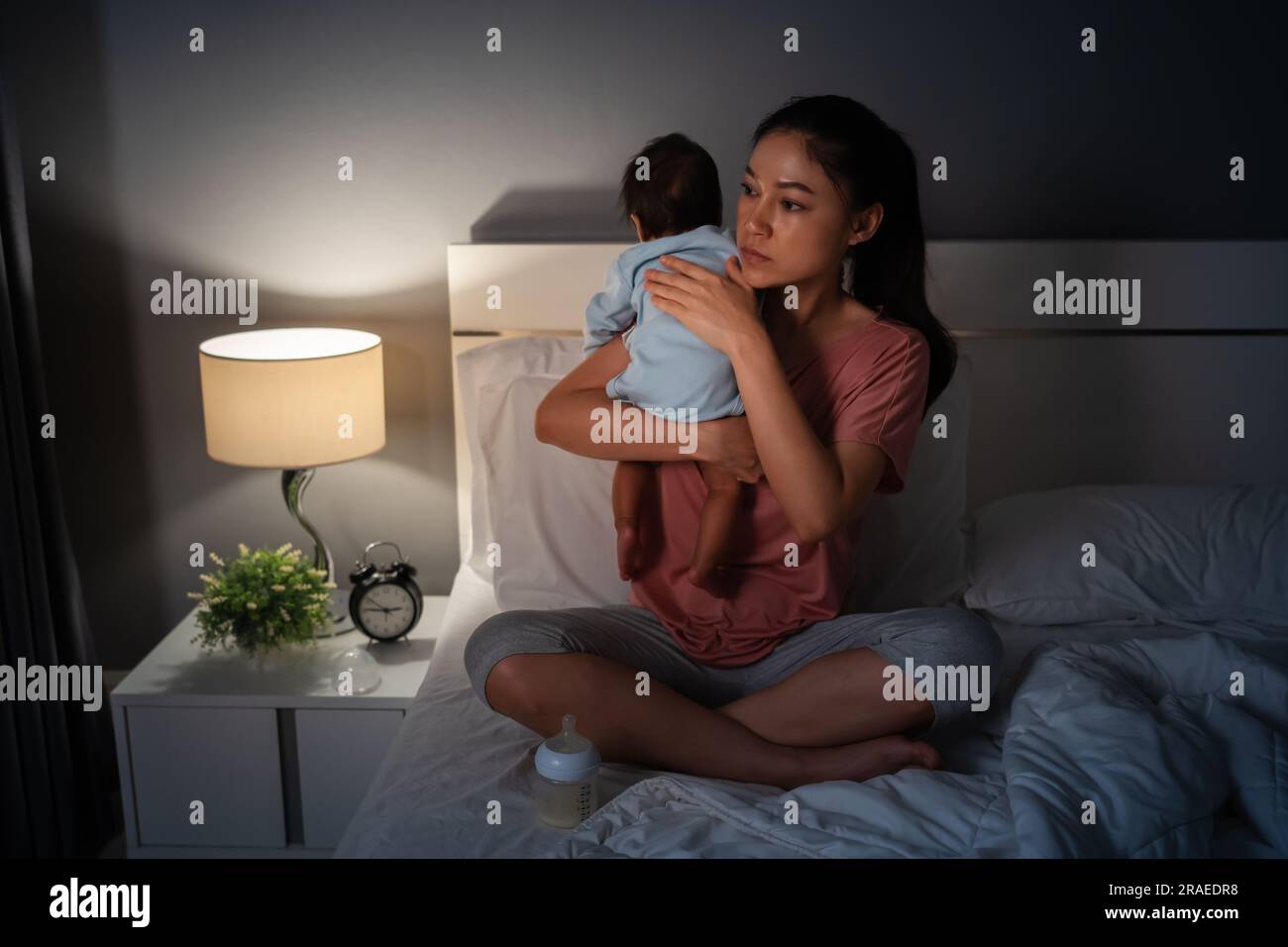 Mutter, die ein Neugeborenes hält und nachts Milch auf einem Bett füttert Stockfoto