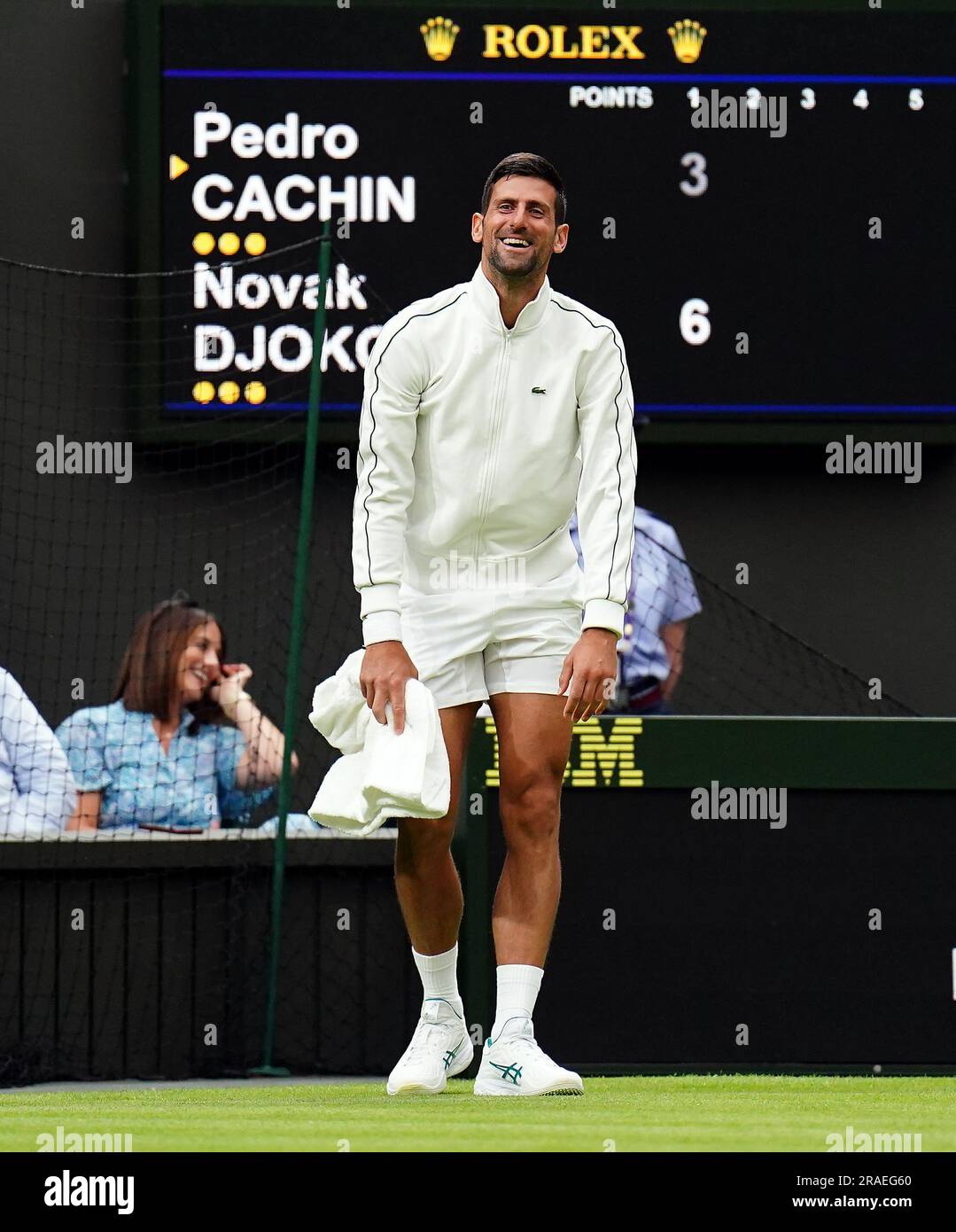 Novak Djokovic untersucht die Feuchtigkeit auf dem Spielfeld und verwendet ein Handtuch, um das Gras während einer verzögerten Regenzeit im Spiel am ersten Tag der Wimbledon Championships 2023 im All England Lawn Tennis and Croquet Club in Wimbledon zu trocknen. Foto: Montag, 3. Juli 2023. Stockfoto