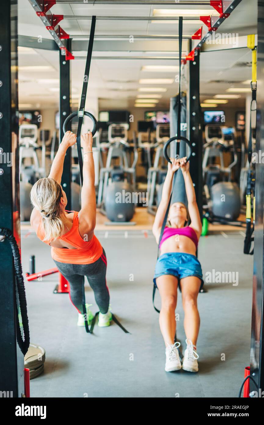 Junge FIT-Frauen, die im Fitnessstudio mit trx-Fitnessgurten Stretching betreiben Stockfoto