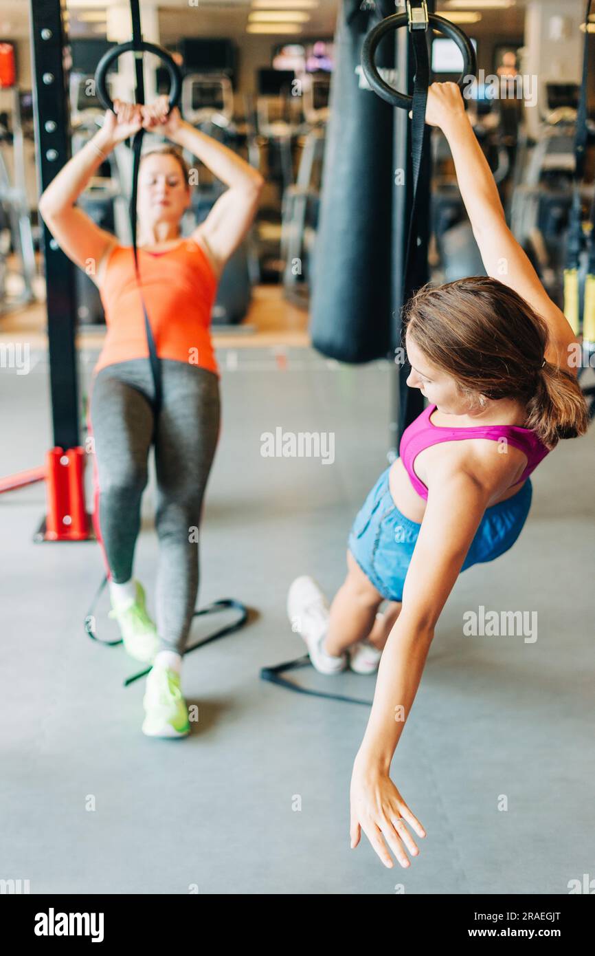 Junge FIT-Frauen, die im Fitnessstudio mit trx-Fitnessgurten Stretching betreiben Stockfoto