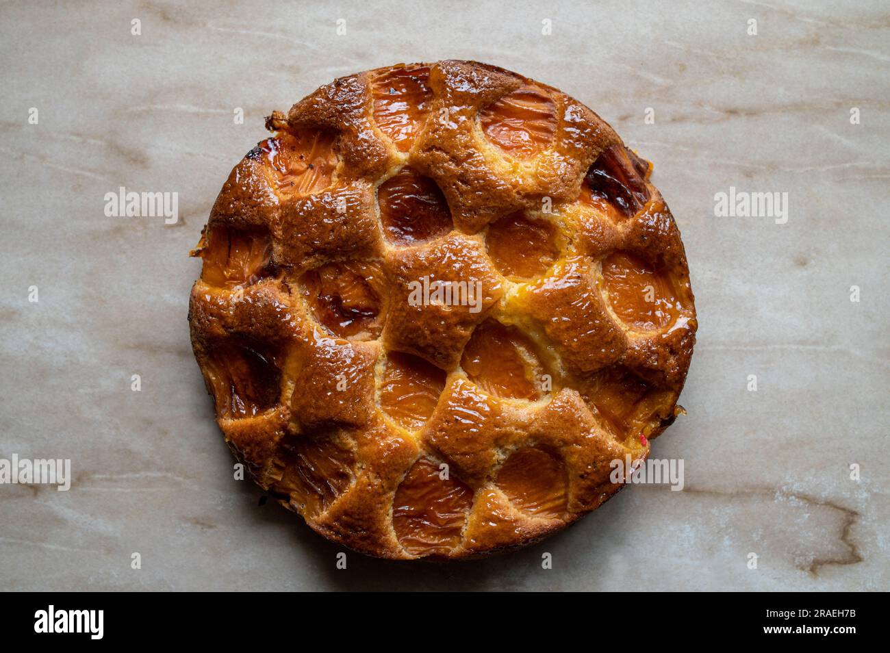 Ganze Aprikosenkuchen mit einem Stück auf einem Kuchenbediener isoliert auf hellem Hintergrund Stockfoto