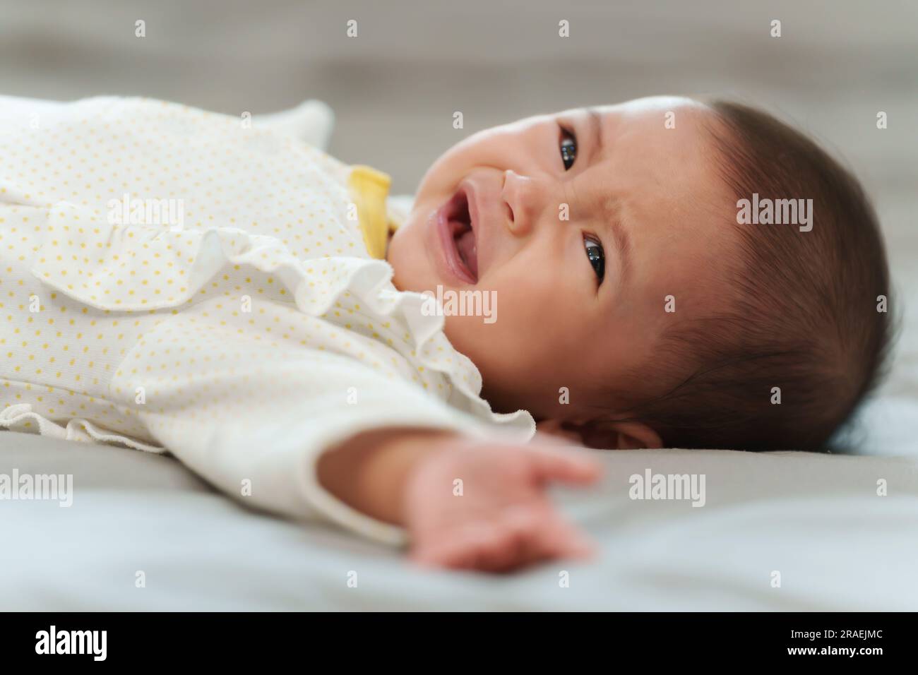 Baby liegt und weint auf einem Bett Stockfoto