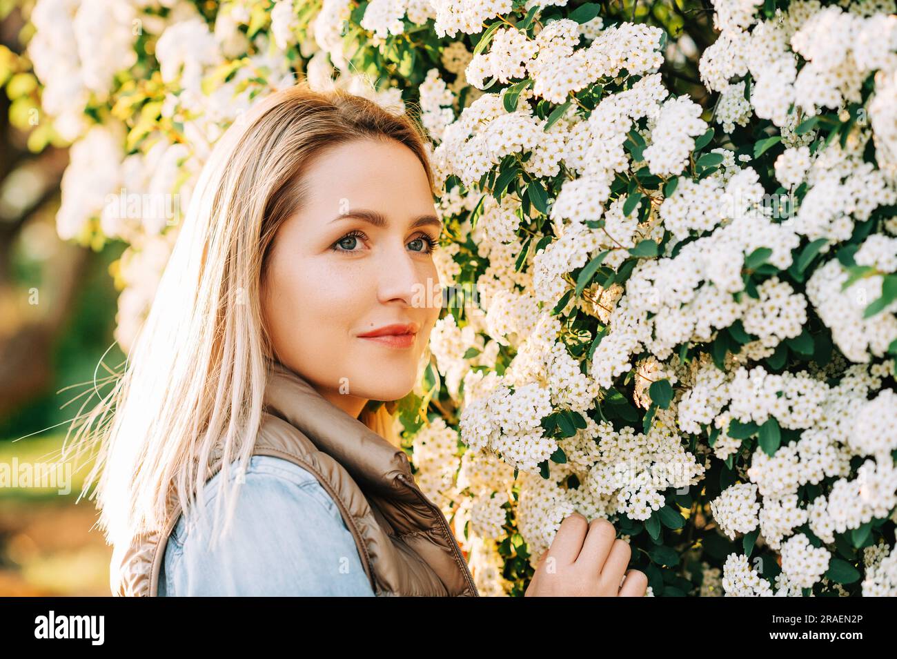 Frühling Nahaufnahme Porträt einer hübschen jungen Frau, die draußen im Blumengarten posiert Stockfoto