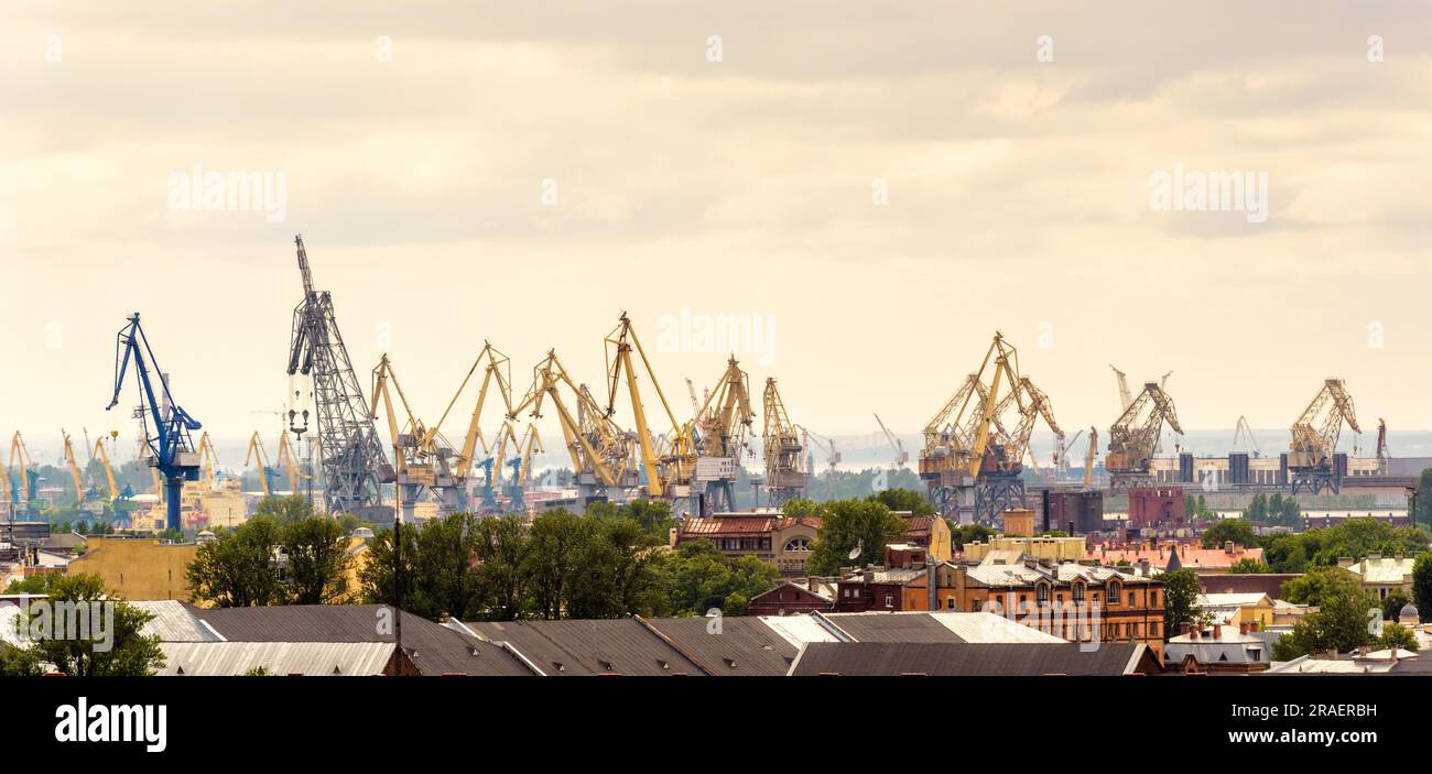 Blick auf Hafenkrane im Hintergrund, Sankt Petersburg, Russland. Skyline von St. Petersburg im Sommer. Industrielandschaft mit Seehafen. Thema von tr Stockfoto