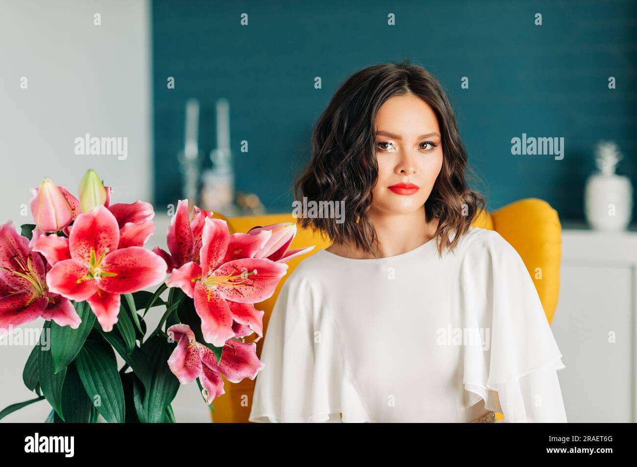 Modeporträt einer wunderschönen jungen asiatischen Frau, die ein weißes Kleid trägt und auf dem Stuhl sitzt Stockfoto