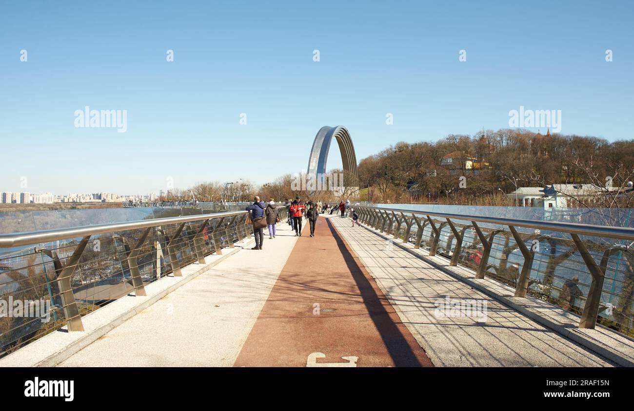 Kiew, Ucraine-03.30.2023: Fußgänger- und Fahrradbrücke über den Abstieg von Saint Volodymyr in Kiew, Ukraine. Glasbrücke, moderne Fußgängerbrücke mit Verbindungstür Hi Stockfoto