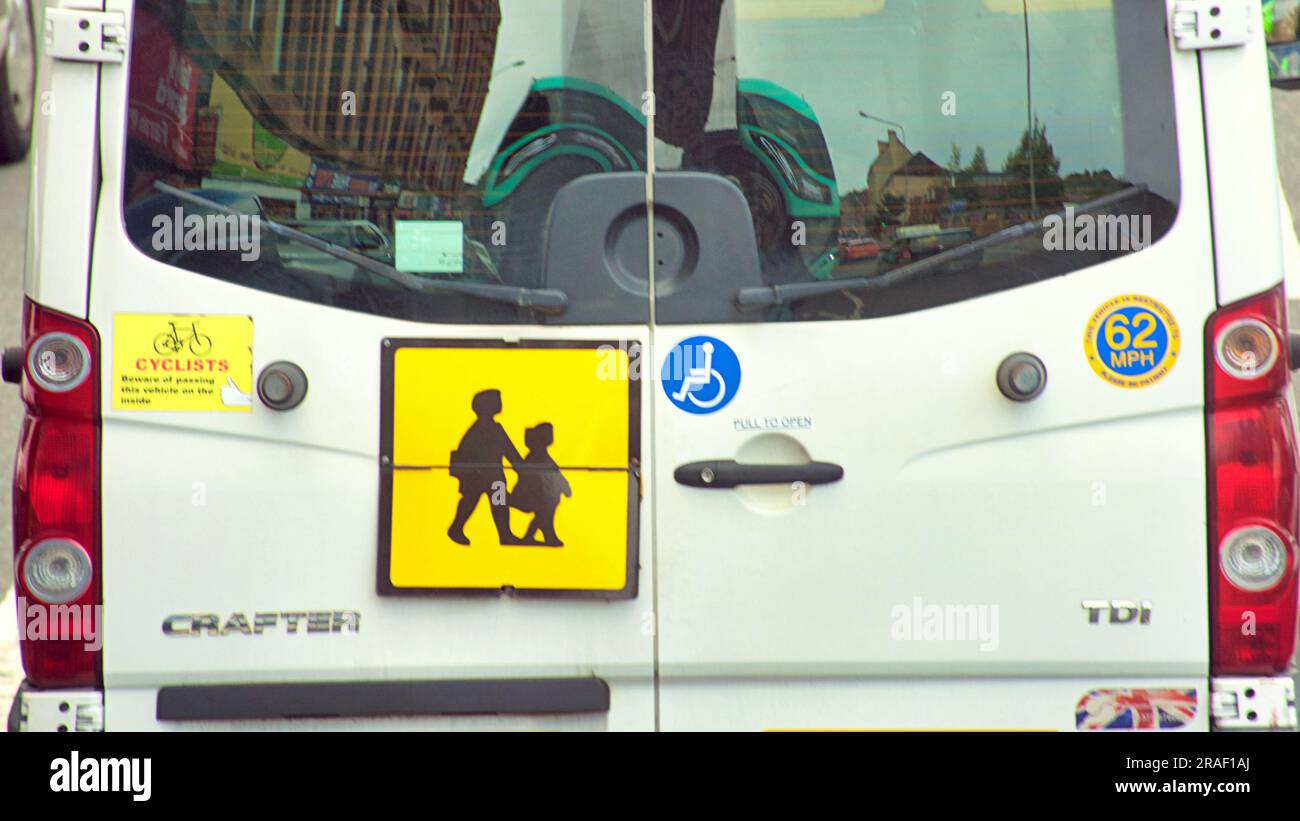 britischer Schulbus hinten gelbes Quadrat mit Mutter-Kind-Symbol Stockfoto
