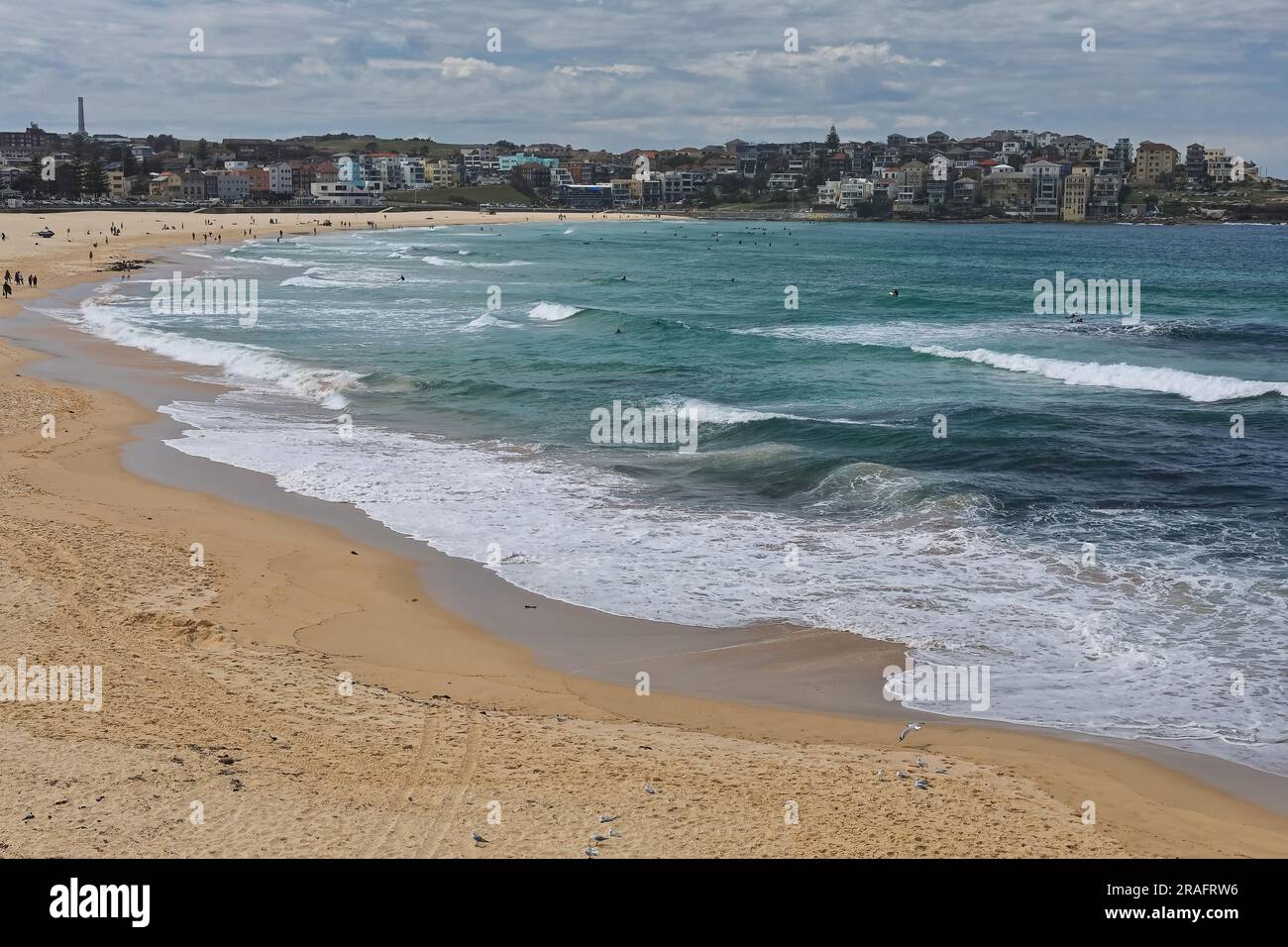 722 Touristen und Strandbesucher laufen am Bondi Beach entlang, während einige Surfer versuchen, auf den Wellen zu reiten. Sydney-Australien. Stockfoto