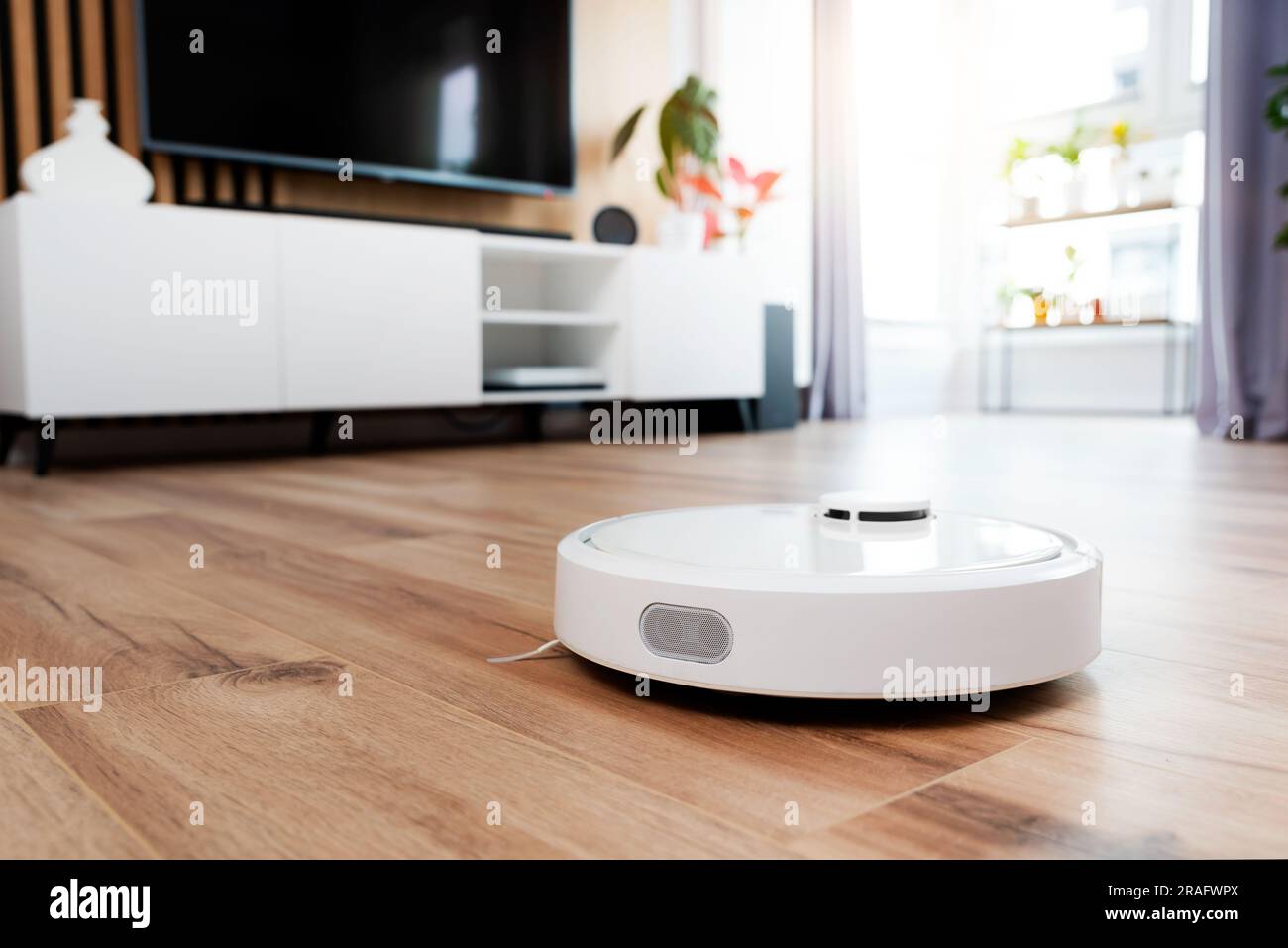 Weißer Roboter-Staubsauger auf dem Boden im Wohnzimmer, Smart-Home-Gerät Stockfoto