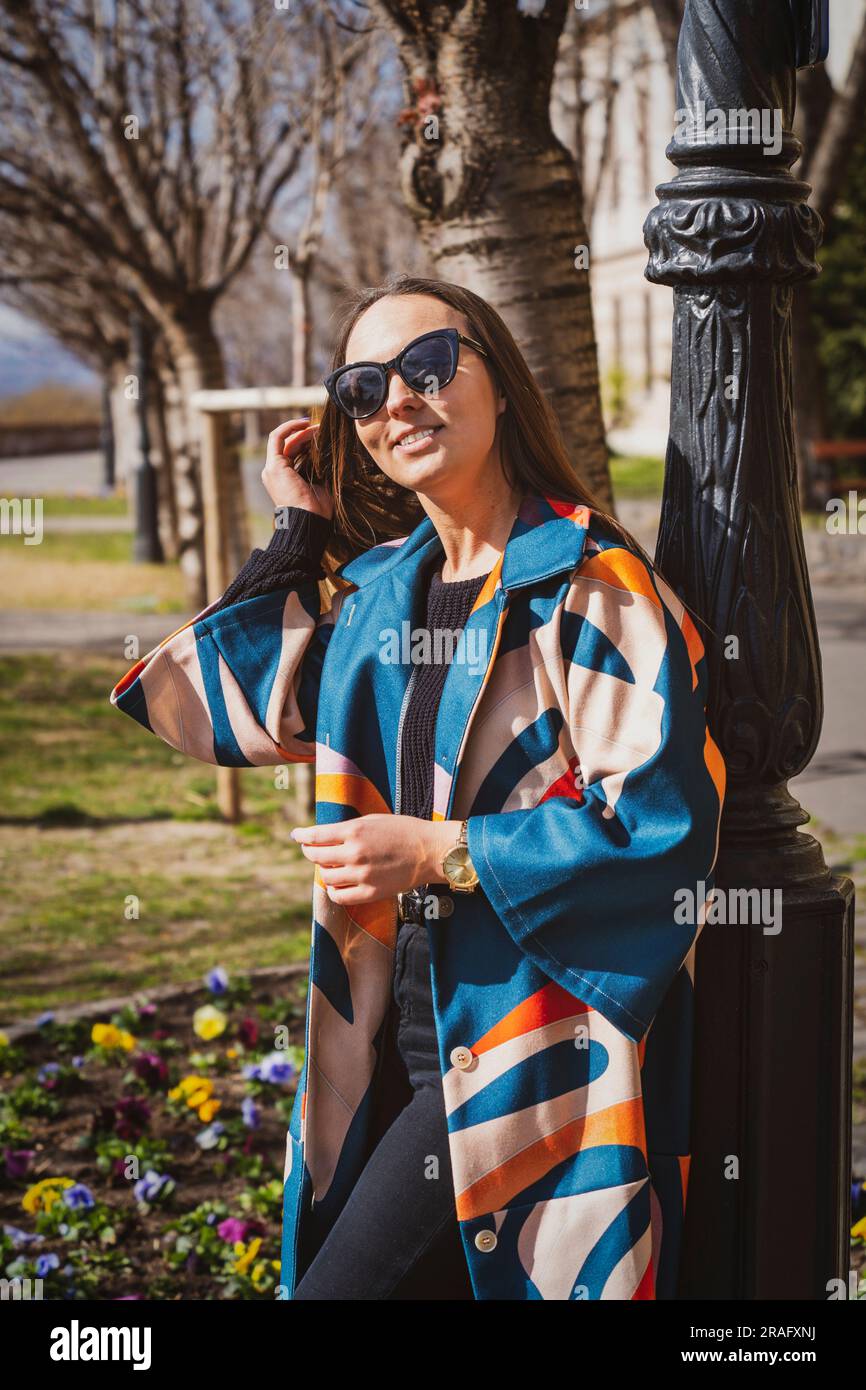 Junge Frau mit Sonnenbrille in einer farbenfrohen Jacke mit Budapest im Hintergrund. Stockfoto