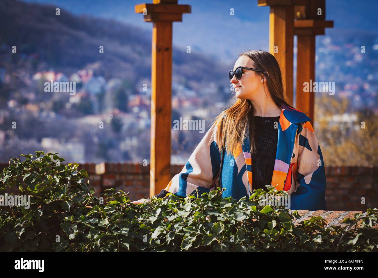 Junge Frau mit Sonnenbrille in einer bunten Jacke in Budapest Stockfoto