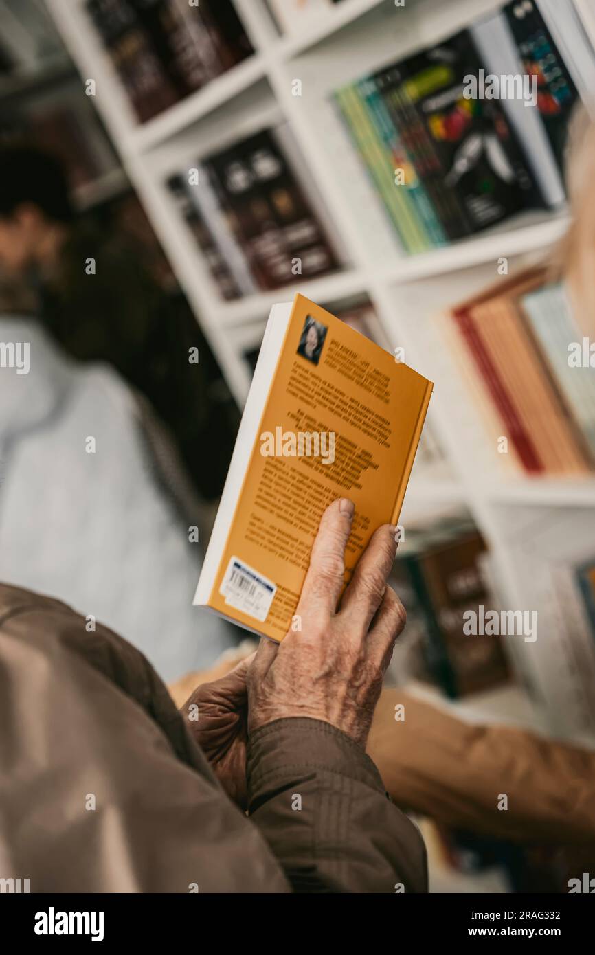 Nahaufnahme der Hände eines älteren Mannes mit offenem Buch, Buchladen. Echte Szene. Lesekonzept, Rente, Interessen im Alter, Lebensstil Stockfoto