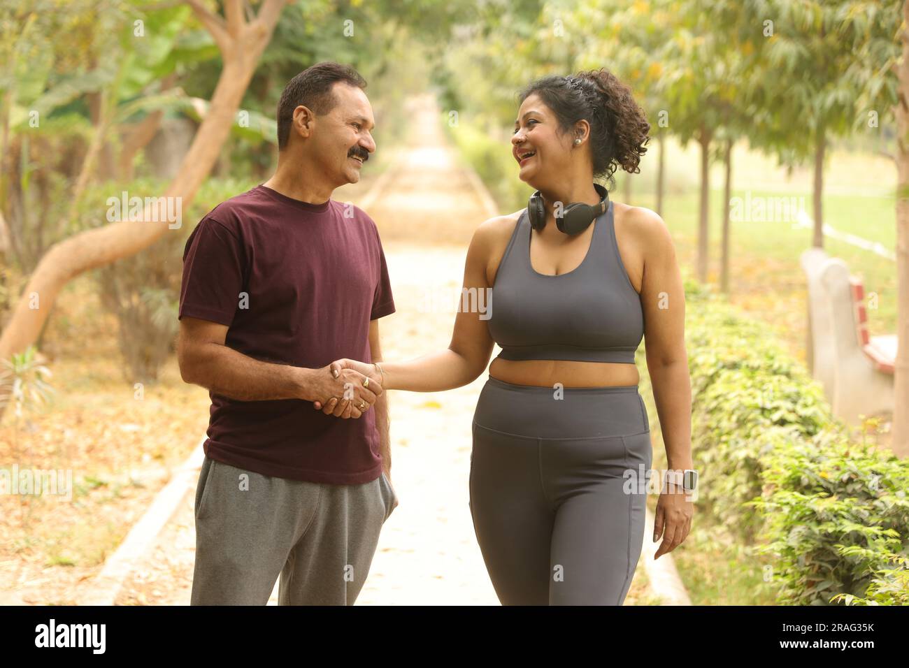 Gesundheitsbewusste Menschen und Freunde, die beim Joggen aufmuntern. Sie machen einen Hi-Five-Wettkampf, wenn sie sich am frühen Morgen auf einer Rennstrecke gegenüberstehen Stockfoto