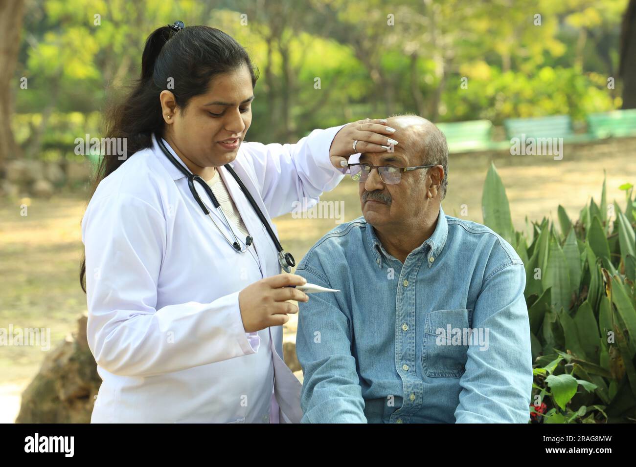 Indische Ärztin untersucht den Seniorpatienten im Stadtpark am Nachmittag. Stockfoto Indische Ärztin untersucht den Seniorpatienten im Stadtpark am Nachmittag. Stockfoto