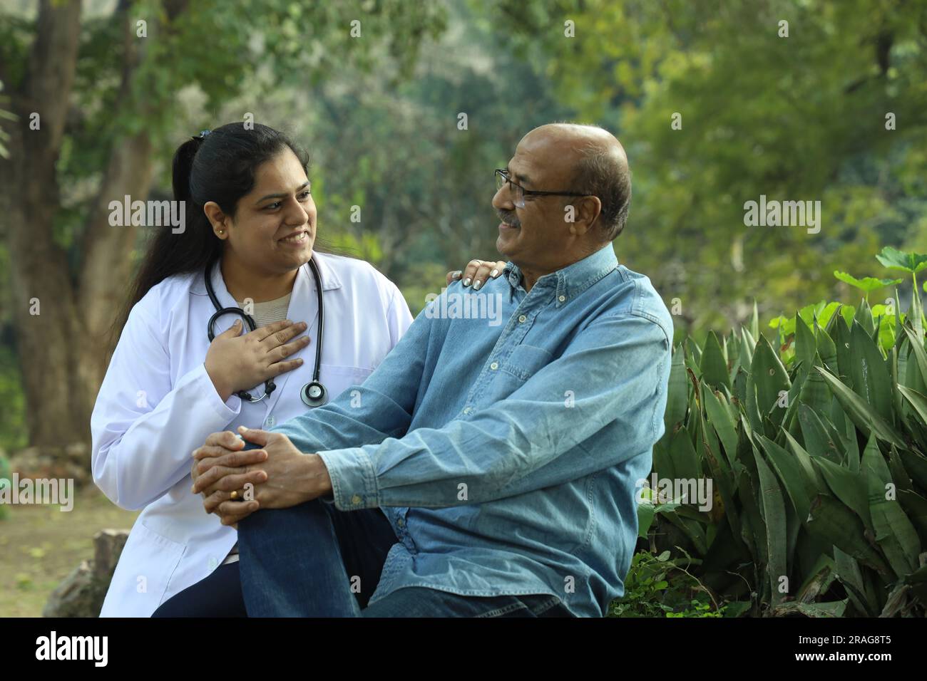 Indische Ärztin untersucht den Seniorpatienten im Stadtpark am Nachmittag. Stockfoto