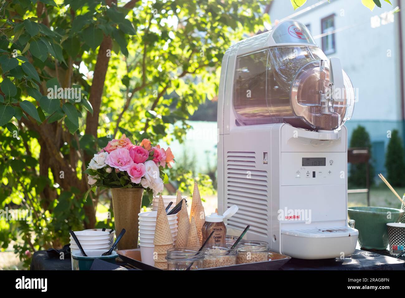 Tallinn, Estland - 30. Juni 2023: Weicheismaschine Ugolini mit Waffelkonusbechern und Streuseln bei einer Sommerparty im Garten. Stockfoto