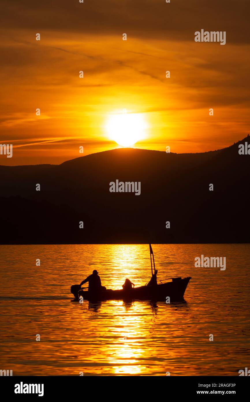 Silhouetted Fischerboot bei Sonnenuntergang - Sveti Stefan, Montenegro Stockfoto