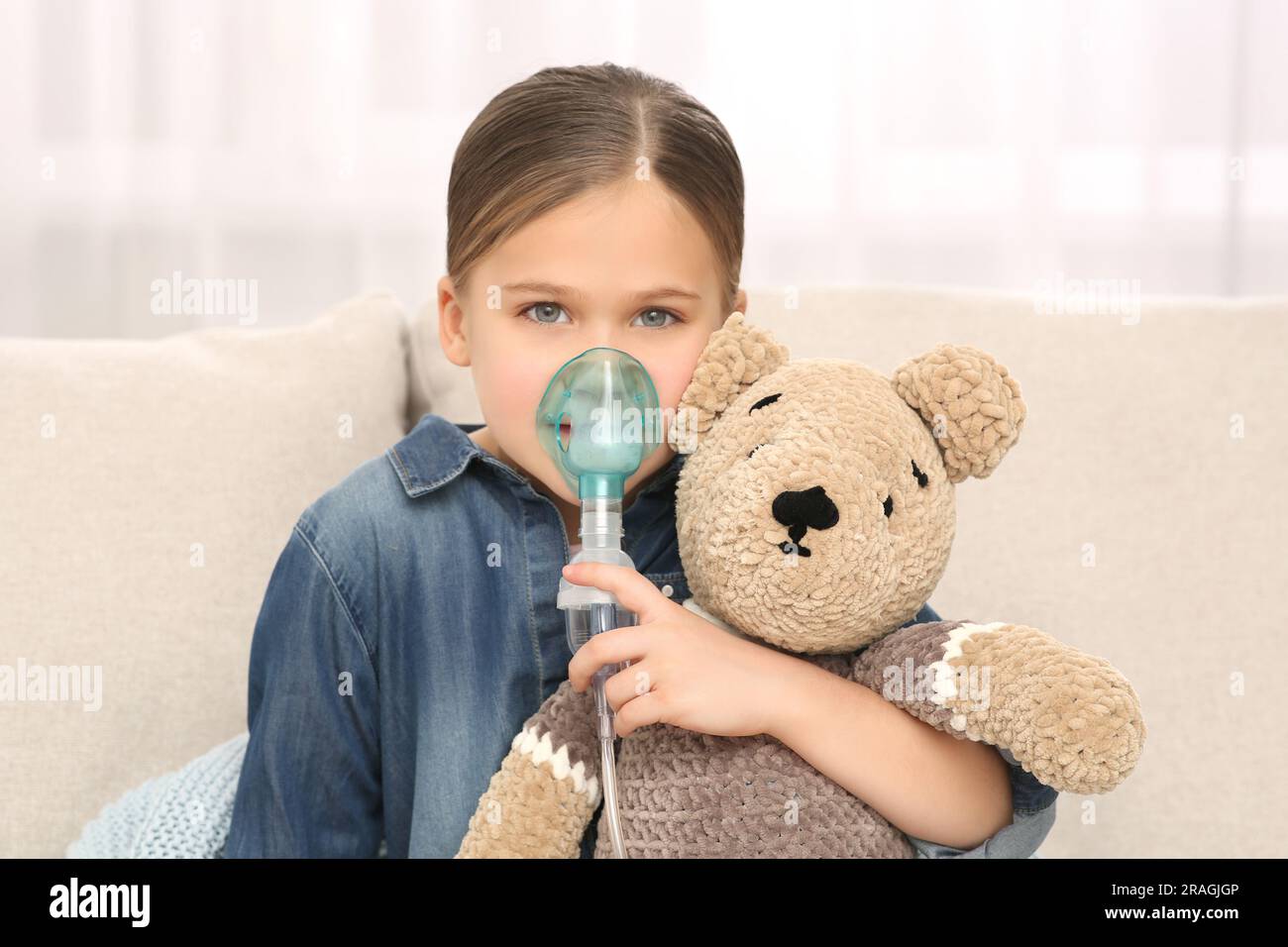 Krankes kleines Mädchen mit Spielzeugbär mit Vernebler zur Inhalation zu Hause Stockfoto