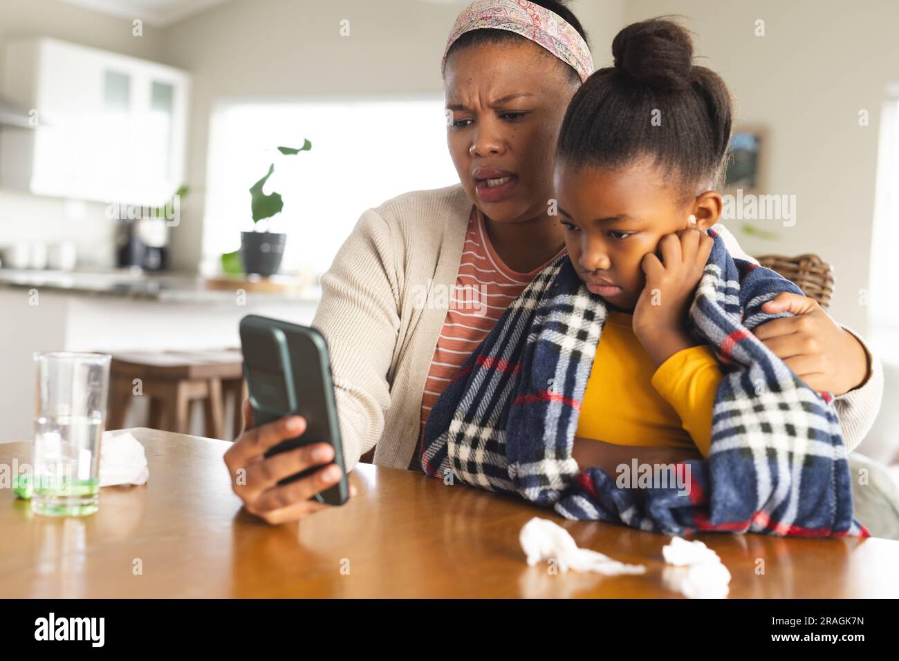 afroamerikanische Mutter und Tochter mit Smartphone zur Online-Beratung mit dem Arzt Stockfoto
