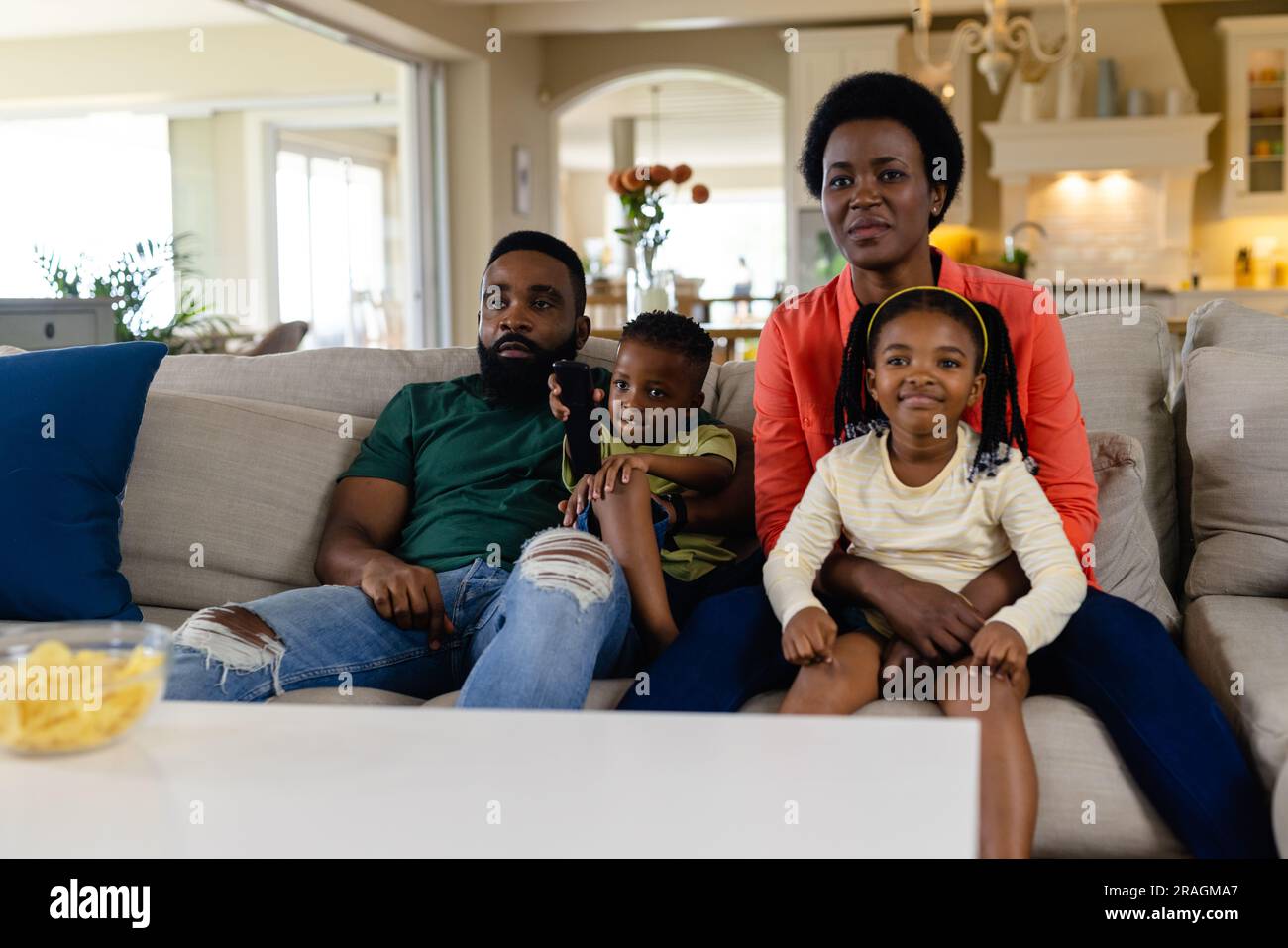 afroamerikanische Eltern und Kinder schauen fern, während sie auf dem Sofa im Wohnzimmer sitzen Stockfoto