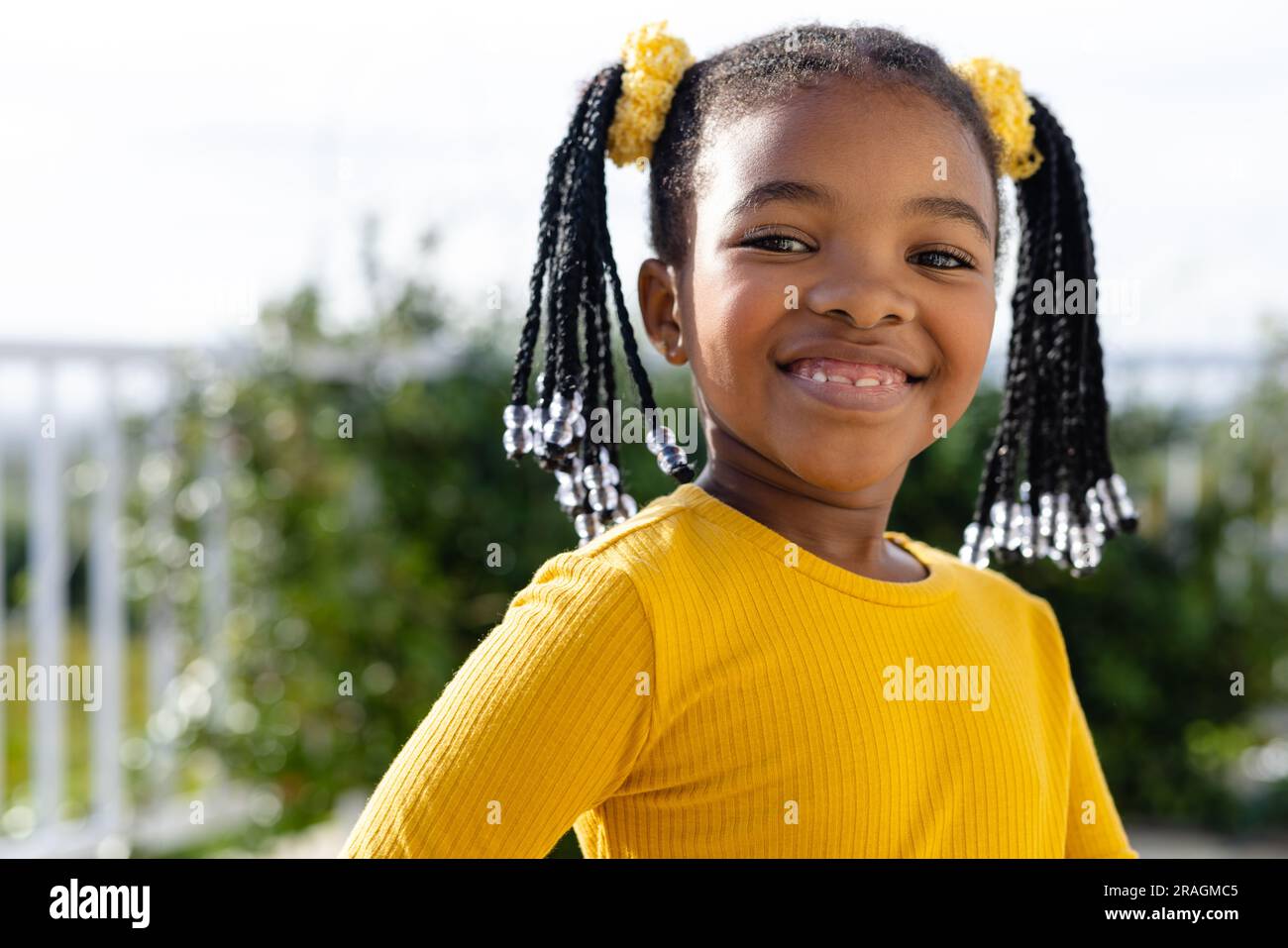 Porträt eines glücklichen afroamerikanischen Mädchens, das auf der sonnigen Terrasse bleibt Stockfoto