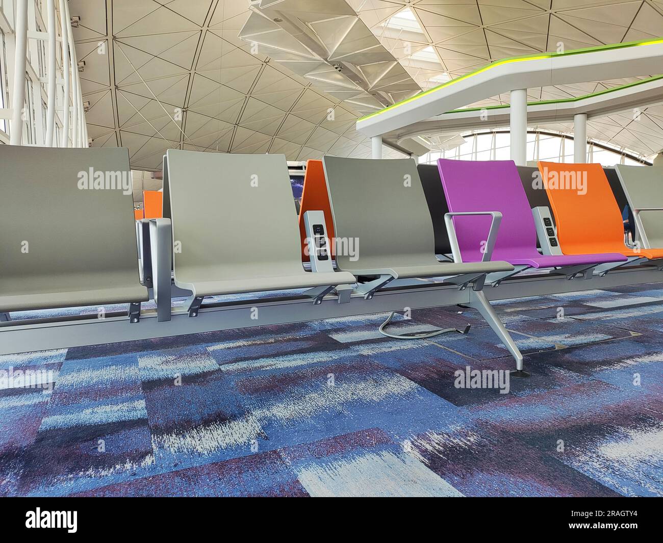 Reihen von farbenfrohen Sitzen in der Halle des Flughafens Stockfoto