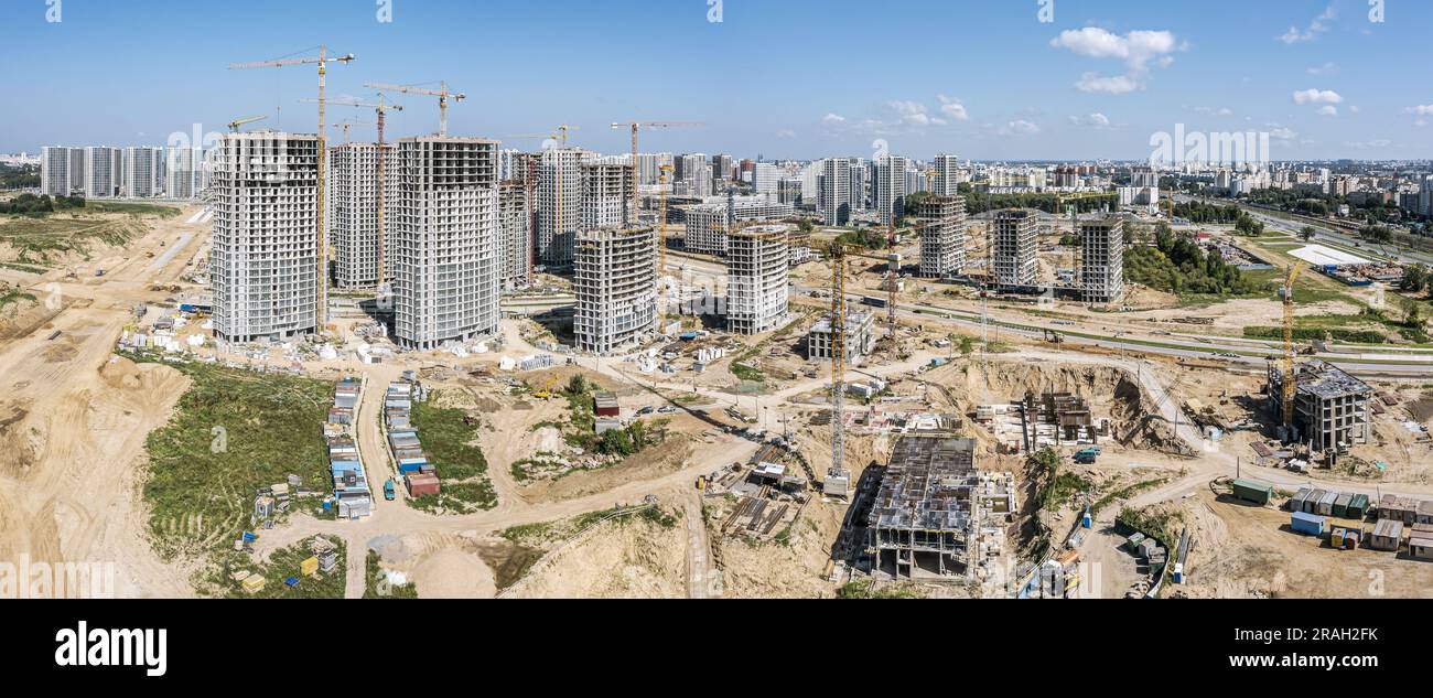 Panoramablick aus der Vogelperspektive auf die Baustelle mit im Bau befindlichen Hochhäusern und Kränen am blauen Himmel Stockfoto