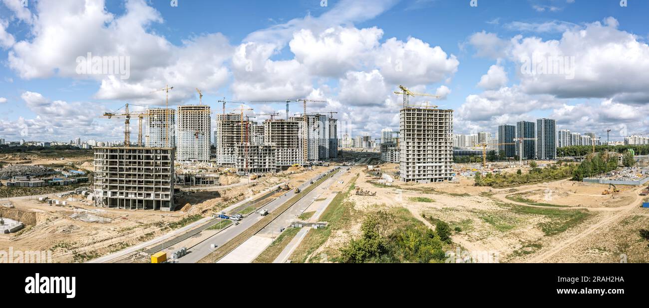 Hochhäuser im Bau und funktionierende Kräne vor blauem bewölktem Himmel. Panoramablick aus der Vogelperspektive. Stockfoto