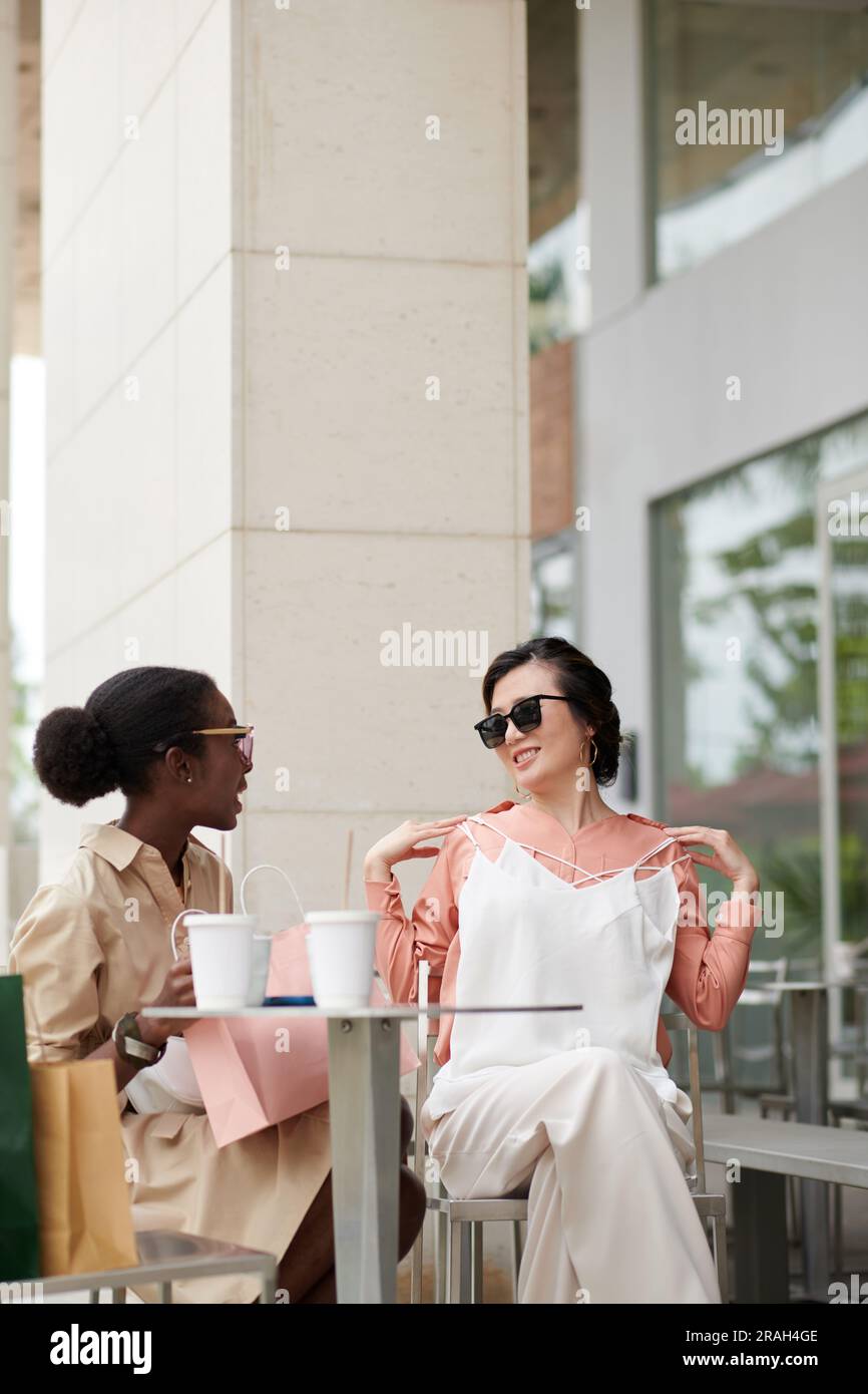 Stilvolle junge Frau, die am Kaffeetisch sitzt und über Einkäufe diskutiert Stockfoto