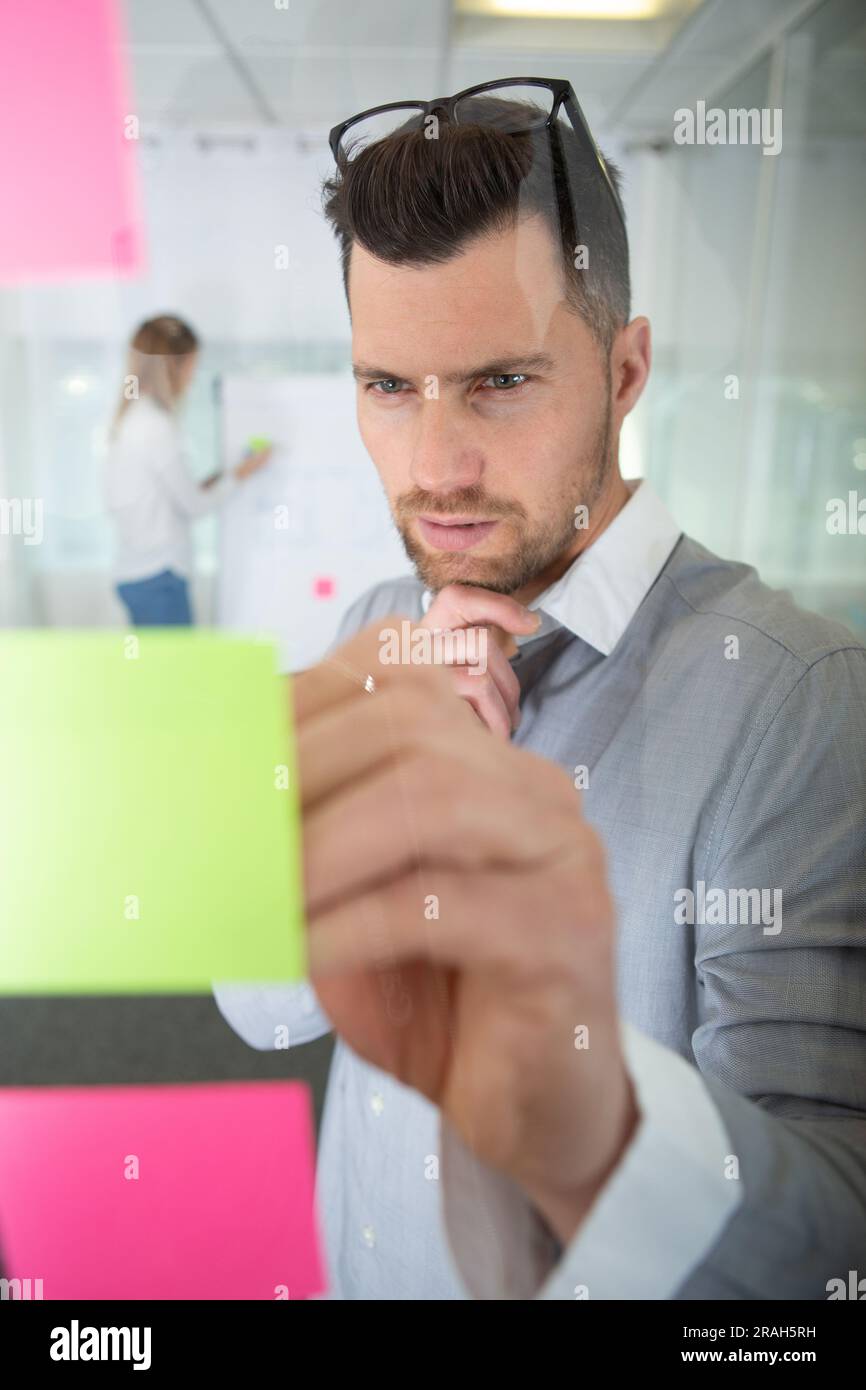 Kreativer Geschäftsmann, der im Büro Notizen auf Papier schreibt Stockfoto