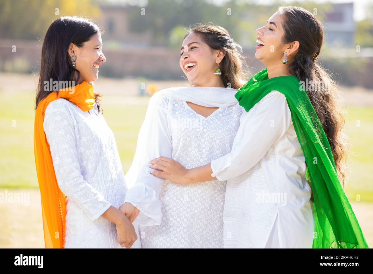 Indischer Unabhängigkeitstag oder republikanisches Tageskonzept. Drei glückliche junge, schöne Frau in traditionellem weißen Kleid, die im Park lacht. Stockfoto