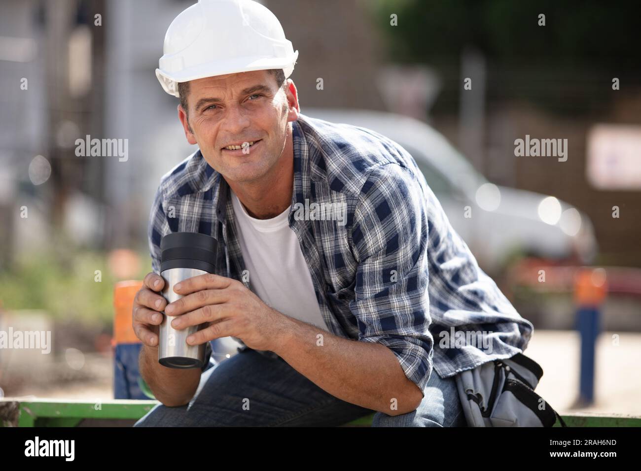 Bauarbeiter in der Pause hält einen isolierten Becher Stockfoto