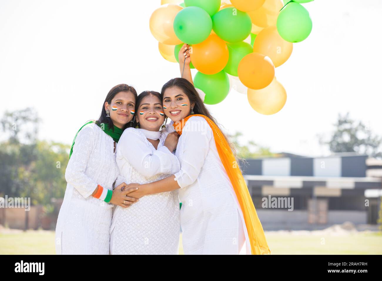 Eine Gruppe wunderschöner glücklicher junger indischer Frauen in traditionellem weißen Kurta-Kleid, die mit dreifarbigen Ballons im Park stehen und den Unabhängigkeitstag feiern Stockfoto