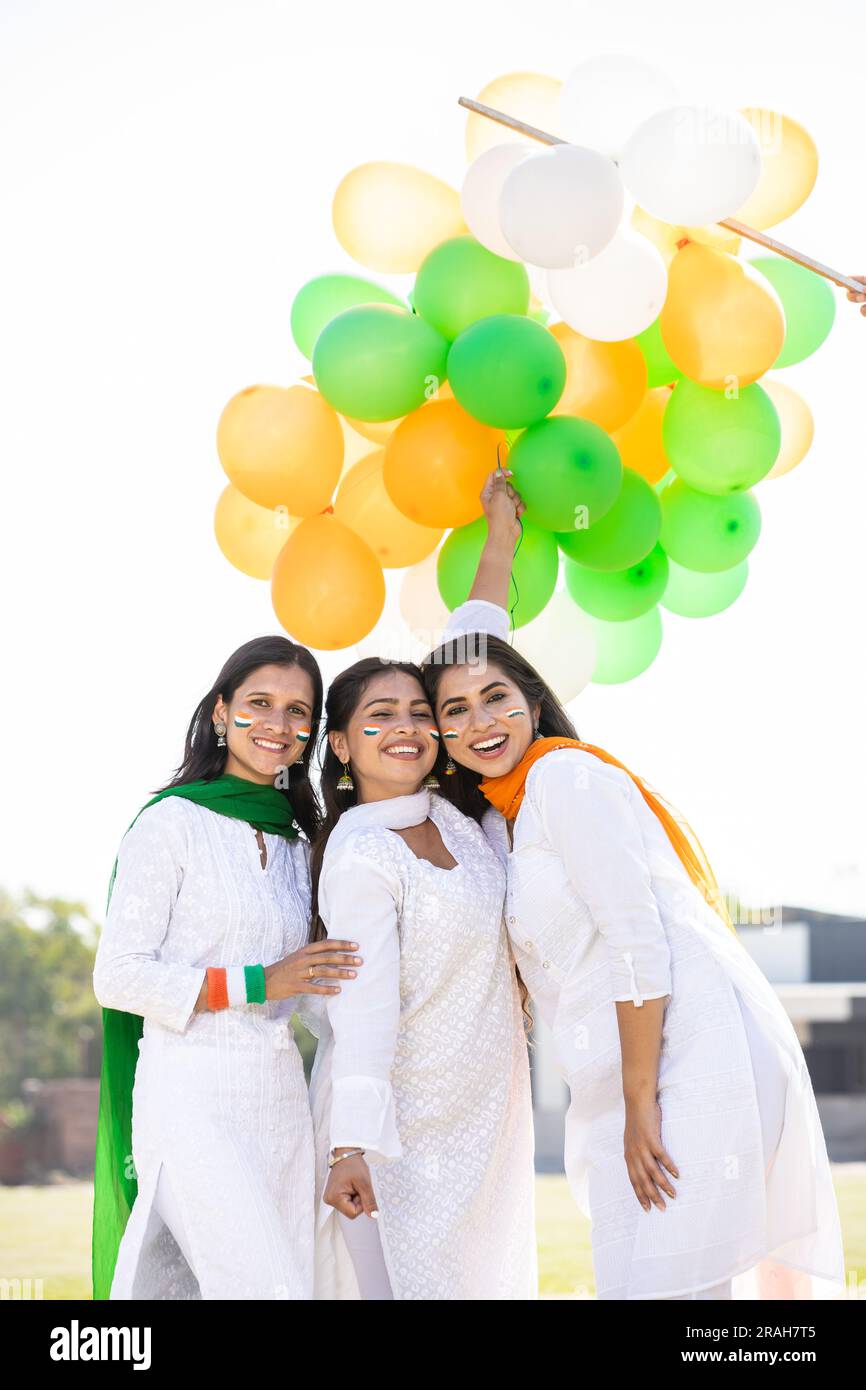 Junge glückliche indische Frauen tragen weiße Kleidung, um den Unabhängigkeitstag oder den tag der republik zu feiern, während sie im Freien dreifarbige Ballons halten. Stockfoto