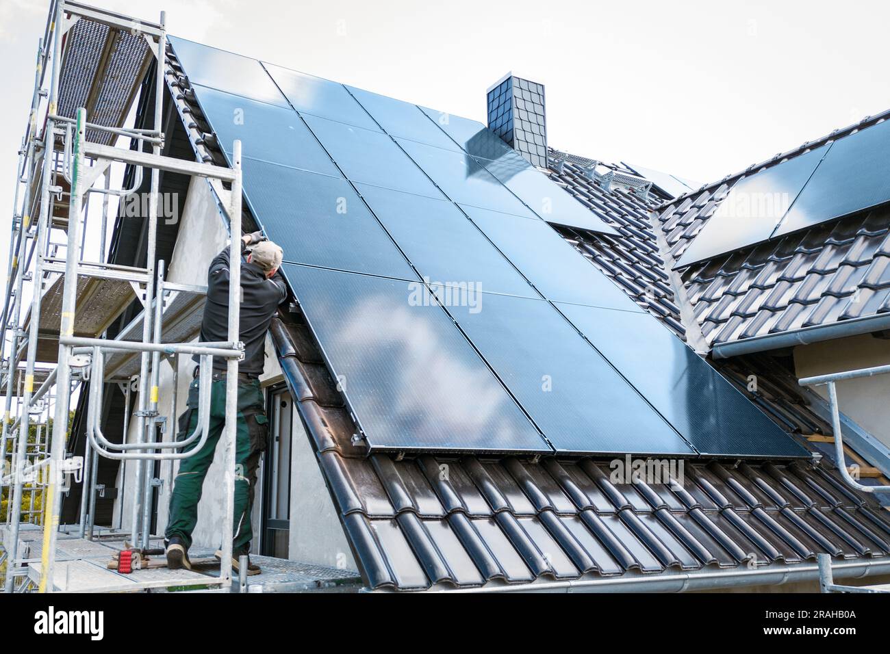 Person, die Solarpaneele auf der Baustelle eines Hauses installiert Stockfoto